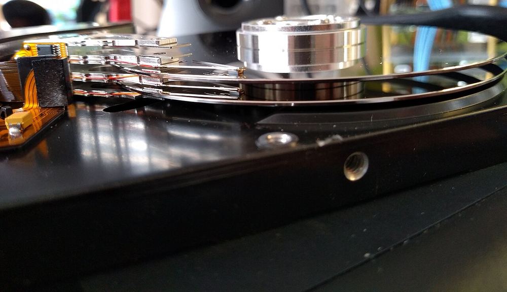 Disco duro abierto visto de lado, con los platos magnéticos y el brazo lector
